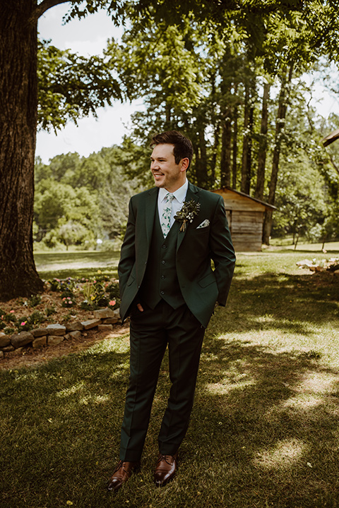 Horse-Range-Vista-groom-standing-by-tree-in-a-green-suit-with-a-floral-tie