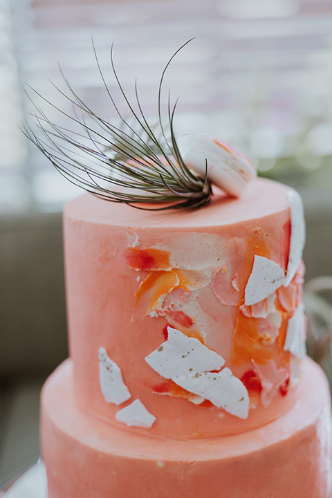 coral colored cake with gold and white designs on it