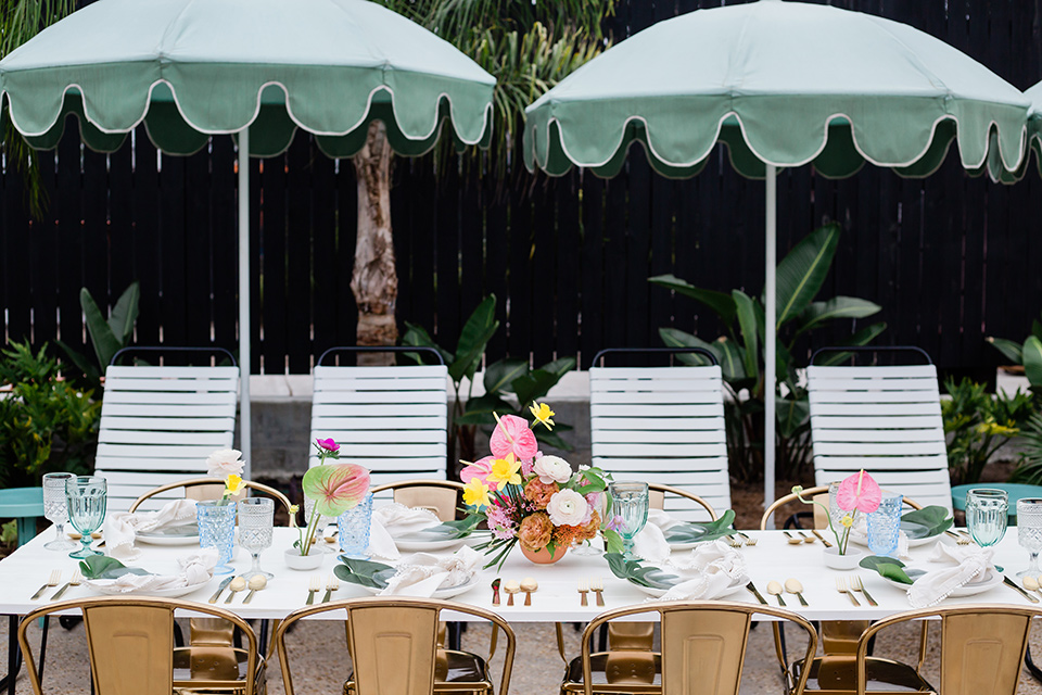 table set up with gold metal farm chairs and mint colored parasols over the table