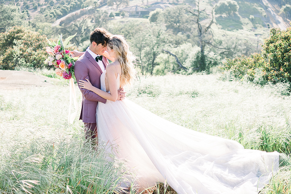 emerald-peak-temecula-wedding-bride-and-groom-in-meadow-bride-in-a-blush-toned-ballgown-with-straps-and-groom-in-rose-pink-suit