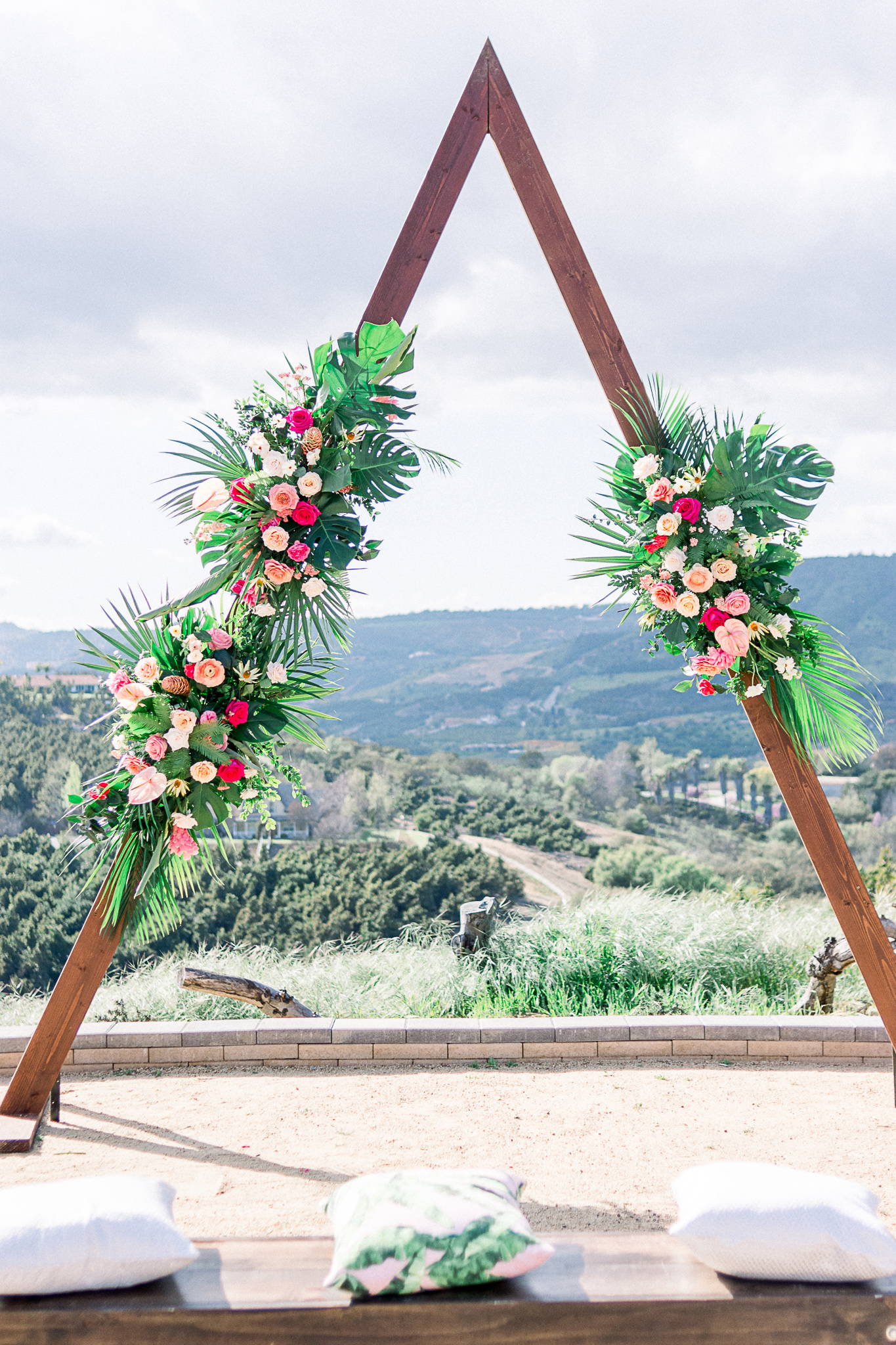 emerald-peak-temecula-wedding-ceremony-arch-in-a-deep-red-wood-in-a-triangle-shape-with-flowers-on-it