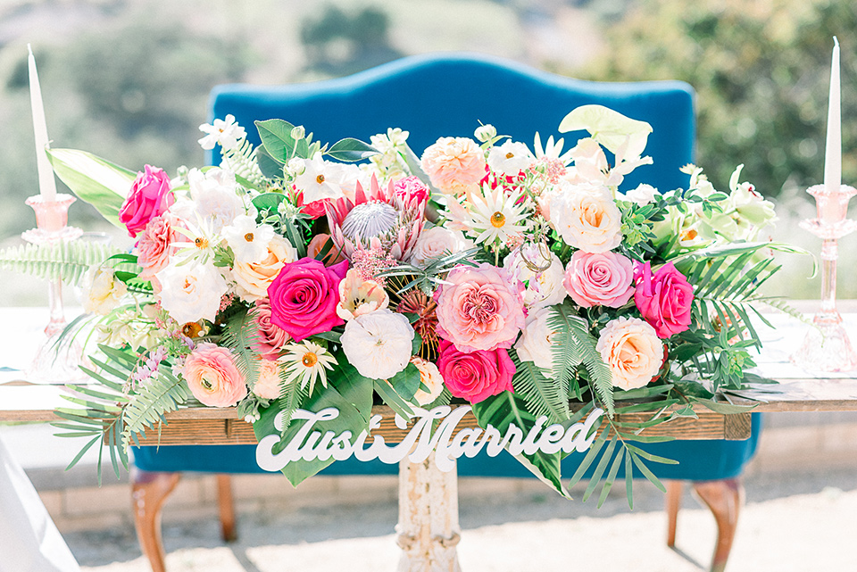 emerald-peak-temecula-wedding-sweetheart-table-with-a-blue-velvet-couch-and-bright-pink-flowers