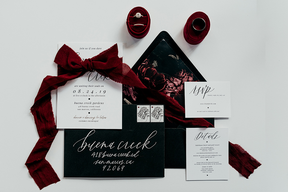  black invitations with white lettering and burgundy velvet ribbon