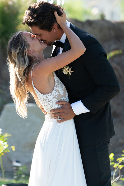 la-bonita-ranch-rustic-shoot-bride-and-groom-about-to-kiss-la-bonita-ranch-rustic-shoot-bridal-gown-with-a-high-neckline-and-a-nude-underlay-groom-in-a-navy-shawl-lapel-tuxedo-with-a-black-bowtie