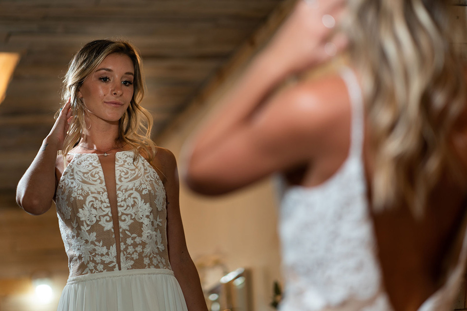 la-bonita-ranch-rustic-shoot-bride-looking-in-the-mirror-the-bride-in-a-white-bohemian-gown-with-a-nude-underlay-and-lace-detailing