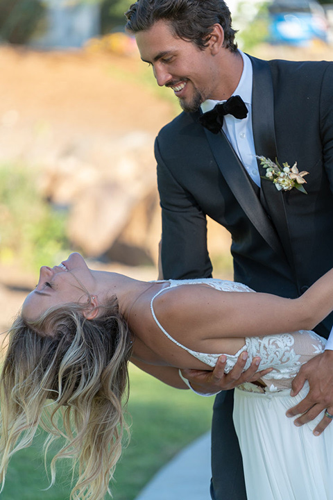 la-bonita-ranch-rustic-shoot-groom-dipping-bride-bride-in-a-white-bohemian-gown-with-a-high-neckline-with-a-lace-groom-in-a-navy-shawl-lapel-tuxedo-with-a-black-bowtie