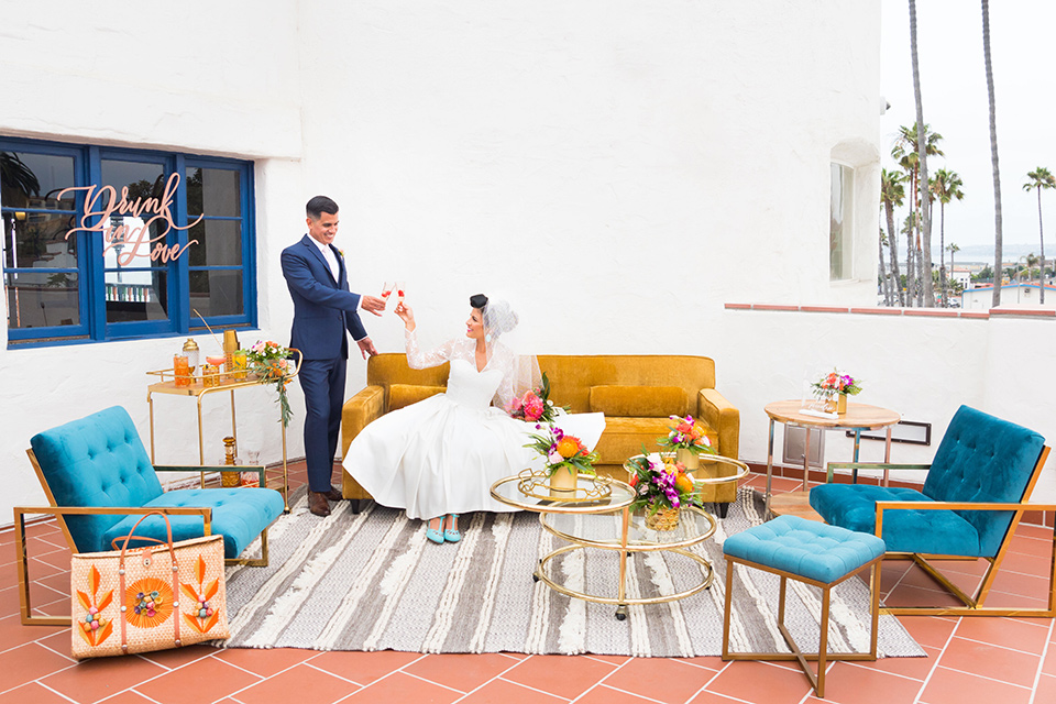 Ole-Hanson-Beach-Club-bride-and-groom-at-reception-area-with-mustard-and-blue-furniture-and-retro-style-rungs-and-decor