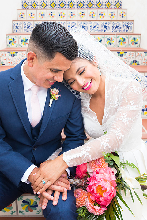 Ole-Hanson-Beach-Club-bride-and-groom-on-steps-the-bride-wore-a-tea-length-retro-inspired-gown-with-lace-sleeves-and-an-elbow-length-veil-and-teal-blue-heels-the-groom-wore-a-dark-blue-suit-with-a-light-pink-long-tie-and-brown-shoes