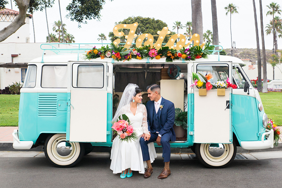 Ole-Hanson-Beach-Club-bride-and-groom-sitting-in-bus-the-bride-wore-a-tea-length-gown-with-lace-sleeves-and-an-elbow-length-veil-and-team-retro-heels-the-groom-wore-a-dark-navy-blue-suit-with-a-blush-pink-long-tie-and-brown-shoes