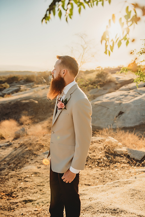 Moonflower-Ranch-Shoot-groom-looking-to-the-side-in-a-tan-suit-jacket-with-burgundy-pants-and-floral-necktie