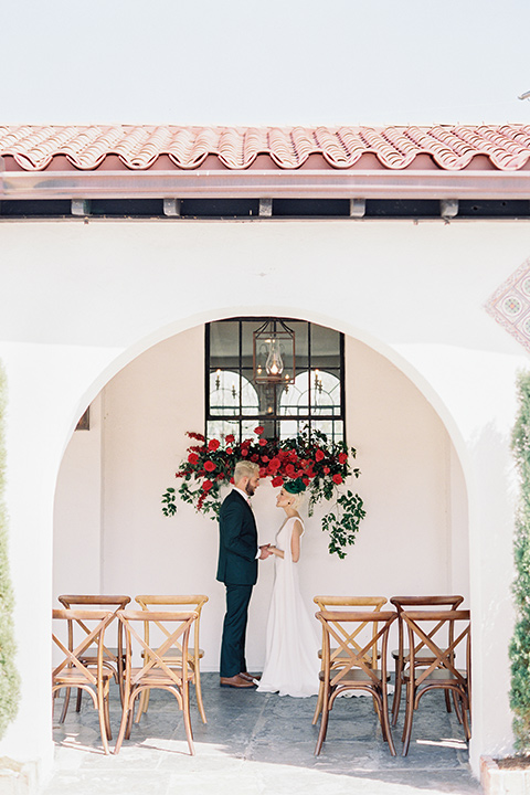 II-Mercato-in-New-Orleans-ceremony-soace-bride-in-a-fitting-minimalistic-dress-with-a-high-neckline-and-floral-crown-groom-in-a-green-suit-with-brown-shoes-and-floral-long-tie