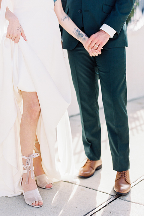 II-Mercato-in-New-Orleans-shoes-bride-in-a-fitting-minimalistic-dress-with-a-high-neckline-and-floral-crown-groom-in-a-green-suit-with-brown-shoes-and-floral-long-tie