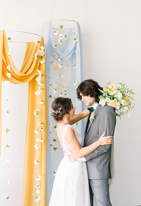 Spring-styled-shoot-bride-and-groom-at-ceremony-space-bridal-gown-with-a-open-back-and-lace-cap-sleeves-and-soft-tulle-skirt-the-groom-is-in-a-grey-suit-with-a-green-velvet-bowtie