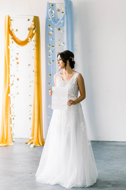 Spring-styled-shoot-bride-standing-bridal-gown-with-a-open-back-and-lace-cap-sleeves-and-soft-tulle-skirt