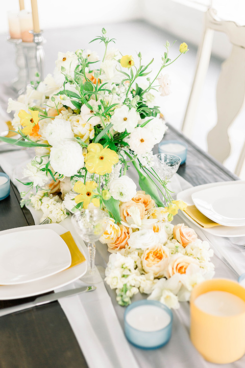 Spring-styled-shoot-decor-on-the-table-with-white-linens-and-yellow-and-blue-candles-and-crystal