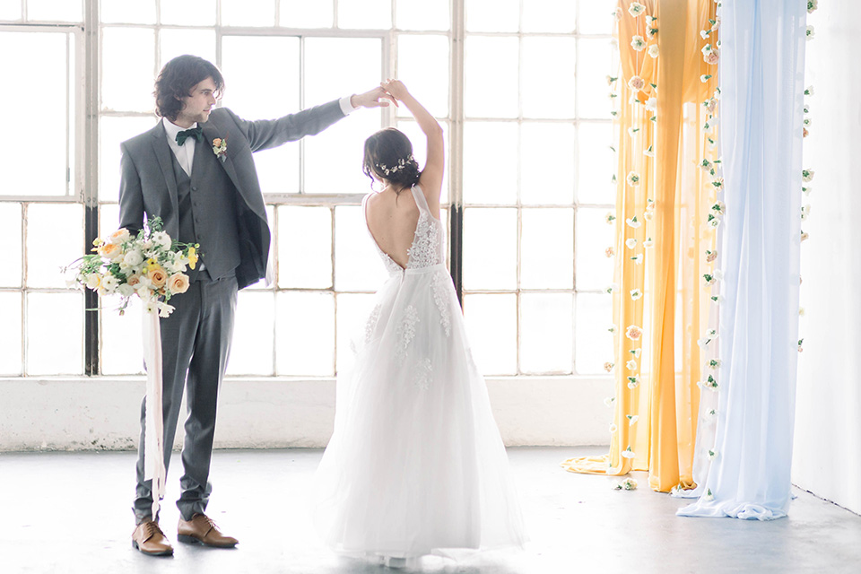 Spring-styled-shoot-groom-twirling-bride-the-bride-wearing-a-soft-tulle-gown-with-a-lace-sweetheart-neckline-and-a-soft-tulle-skirt-the-groom-in-a-grey-suit-with-a-deep-green-velvet-bow-tie