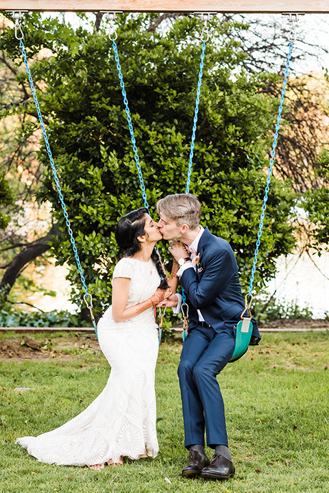 Supriya-and-Chris-wedding-bride-and-groom-on-swings-the-bride-in-a-lace-gown-and-the-groom-in-a-navy-suit-with-pink-bow-tie