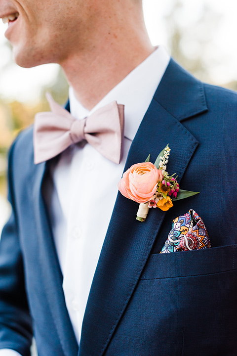 Supriya-and-Chris-wedding-close-up-on-groom-attire-with-a-navy-suit-and-pink-bow-tie