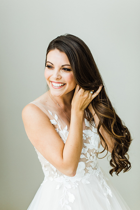 bride in a full tulle ballgown with a crystal and lace bodice and straps, groom in a blue suit with a floral tie and brown shoes