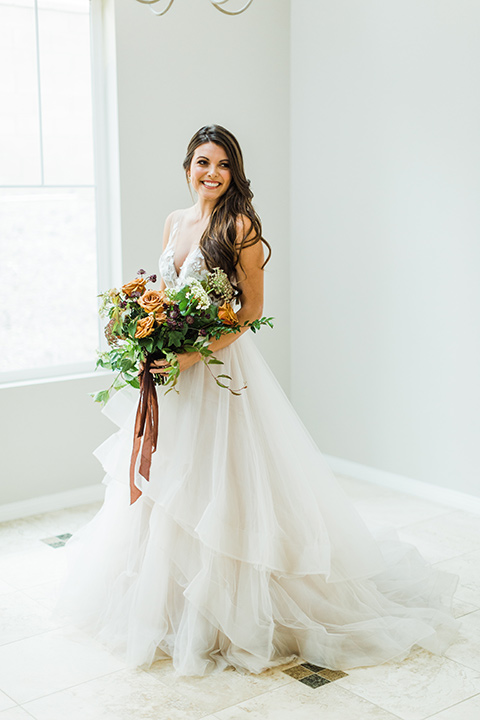  bride in a full tulle ballgown with a crystal and lace bodice and straps, groom in a blue suit with a floral tie and brown shoes 