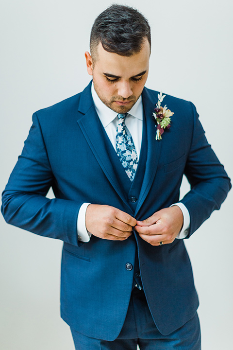 bride in a full tulle ballgown with a crystal and lace bodice and straps, groom in a blue suit with a floral tie and brown shoes