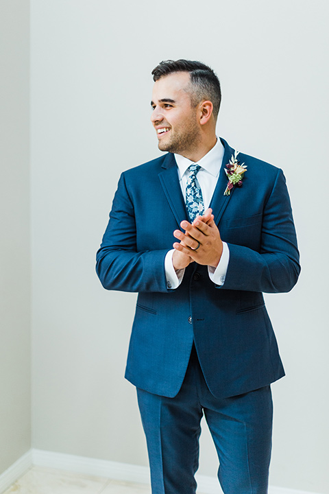  bride in a full tulle ballgown with a crystal and lace bodice and straps, groom in a blue suit with a floral tie and brown shoes 