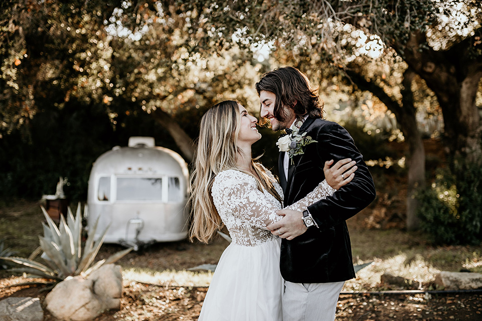 The-Retro-Ranch-Shoot-bride-and-groom-dancing-bride-in-a-boho-gown-with-long-lace-sleeves-and-groom-in-a-velvet-tuxedo-jacket-in-black-with-light-grey-pants