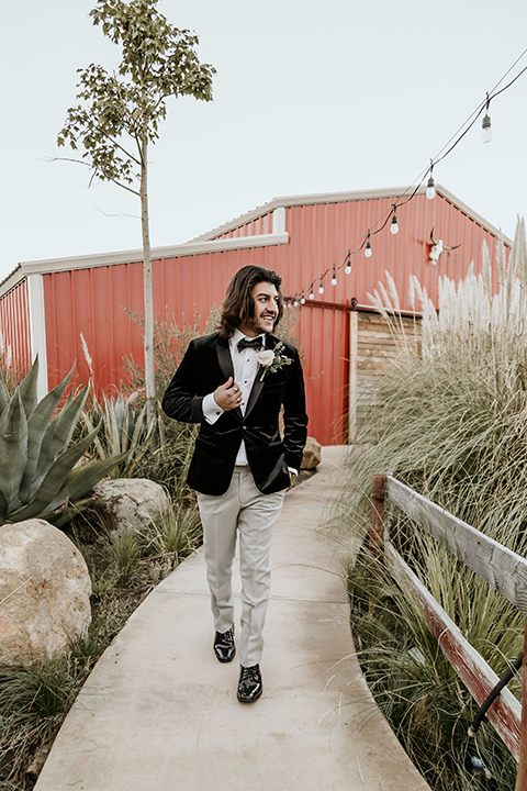 The-Retro-Ranch-Shoot-groom-walking-in-a-black-velvet-coat-with-grey-pants