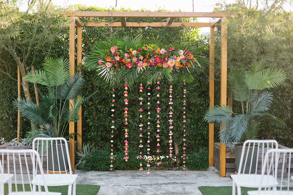 The-Ruby-Street-70s-Inspired-Shoot-ceremony-space-with-hanging-bright-colored-florals-and-white-chairs