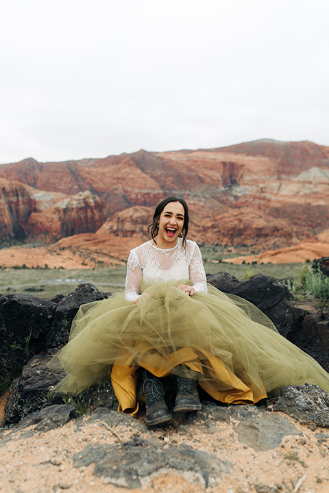 Utah-snow-canyon-shoot-bride-with-hiking-boots-wearing-an-olive-green-tulle-skirt-and-an-ivory-lace-crop-top-with-long-sleeves