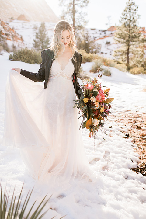 Utah-Shoot-bridal-holding-dress-in-snow-bride-in-a-tulle-flowing-gown-with-a-leather-jacket