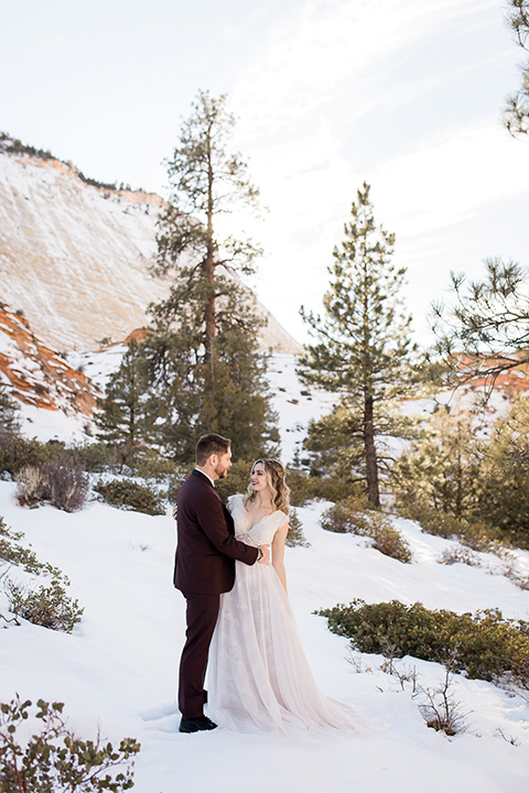 Utah-Shoot-bride-and-groom-looking-at-each-other-bride-in-a-flowing-tulle-gown-with-a-leather-jacket-and-the-groom-in-a-burgundy-jacket-with-a-black-long-tie