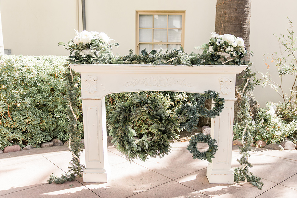 Maxwell-House-ceremony-set-up-with-a-white-firsplace-inspired-wedding-arch-with-greenery-and-florals