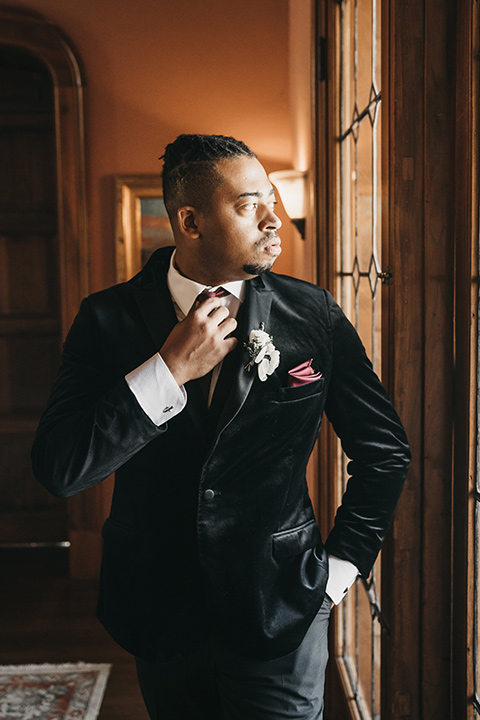 Maxwell-House-groom-looking-out-the-window-with-a-black-velvet-tuxedo-and-a-red-long-tie