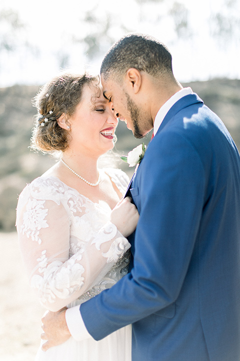 community-church-wedding-bride-and-groom-touching-heads-bride-in-a-flowing-gown-with-long-sleeves-and-an-illusion-bodice-groom-in-a-cobalt-blue-suit-with-a-berry-colored-tie