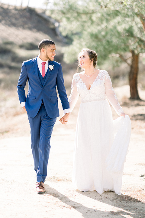 community-church-wedding-bride-and-groom-walking-amiling-at-each-other-bride-in-a-flowing-boho-style-dress-with-sleeves-groom-in-a-royal-blue-suit-with-berry-tie