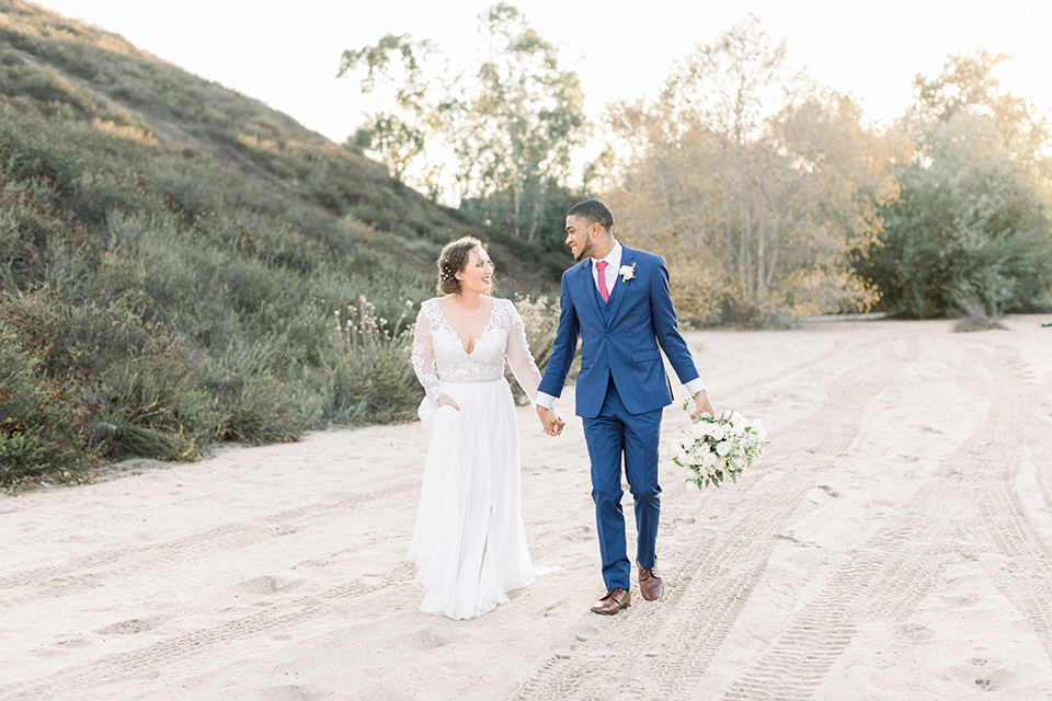 comminuty-church-wedding-bride-and-groom-walking-bride-in-a-flowing-gown-with-long-sleeves-and-an-illusion-bodice-groom-in-a-cobalt-blue-suit-with-a-berry-colored-tie