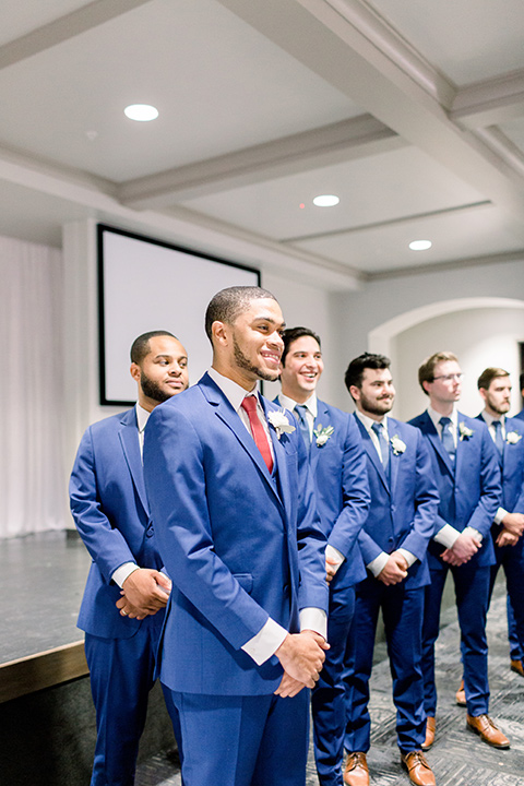 community-church-wedding-groom-at-end-of-aisle-waiting-groom-in-a-royal-blue-suit-with-berry-tie