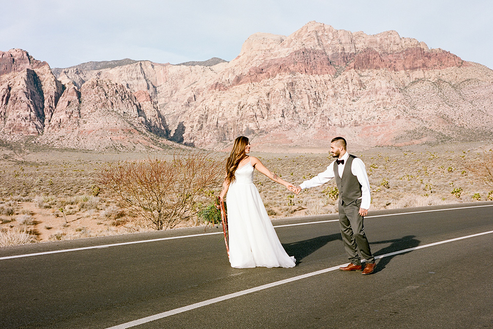 red-rocks-shoot-bride-and-groom-in-streets-bride-wearing-a-flowing-white-gown-and-groom-in-a-charcoal-grey-suit