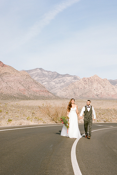 red-rocks-shoot-bride-and-groom-walking-in-the-street-bride-in-a-flowing-white-gown-groom-in-a-grey-suit