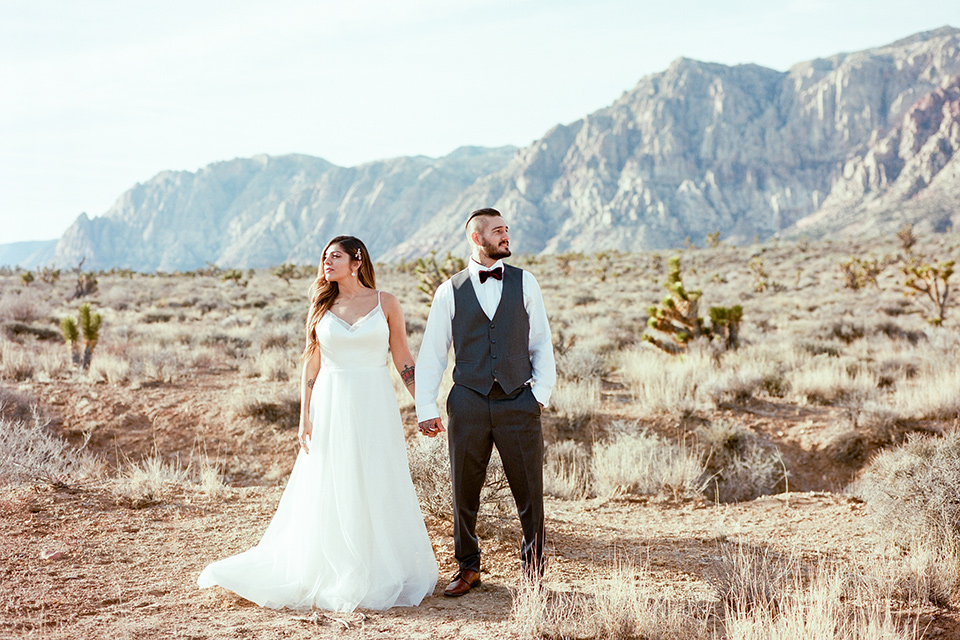 red-rocks-shoot-looking-away-bride-in-a-flowing-white-gown-groom-with-grey-suit