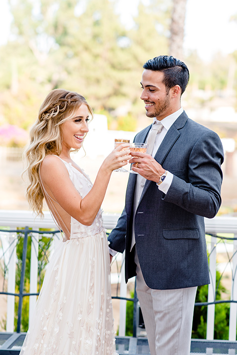 Blossom-valley-victorian-wedding-shoot-bride-and-groom-drinking-bride-wearing-a-tulle-ballgown-with-a-deep-v-and-groom-wearing-a-mix-and-match-look-with-light-grey-pants-and-a-dark-grey-coat