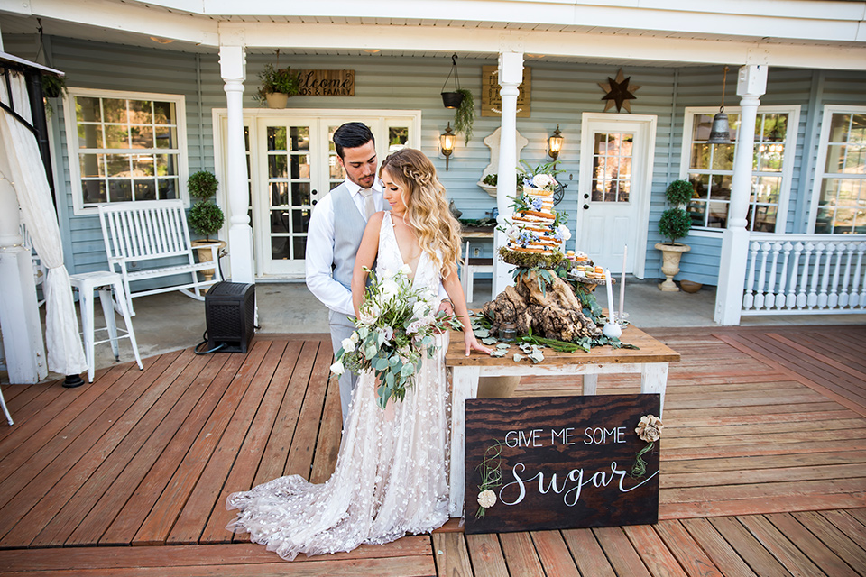 Blossom-valley-victorian-wedding-shoot-bride-and-groom-in-front-of-the-venue-bride-weaing-a-flowing-gown-with-straps-and-groom-wore-a-mix-and-match-look-with-a-dark-grey-coat-and-light-grey-pants