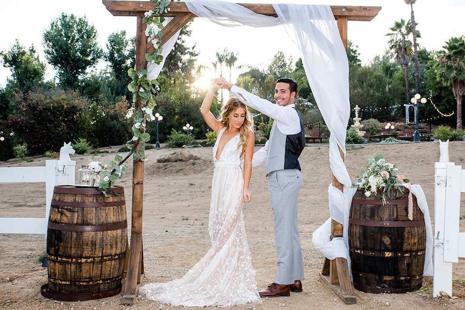 Blossom-valley-victorian-wedding-shoot-bride-and-groom-spinning-bride-weaing-a-flowing-gown-with-straps-and-groom-wore-a-mix-and-match-look-with-a-dark-grey-coat-and-light-grey-pants