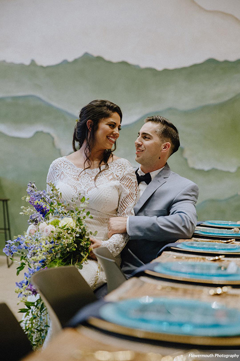 gather-venues-bride-sitting-on-grooms-lap-bride-in-a-lace-gown-groom-in-a-light-blue-suit