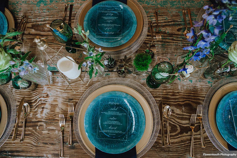 gather-venues-overhead-view-of-table-set-up-and-décor-with-blue-charger-plates-with-mixed-metal-décor-and-utensils