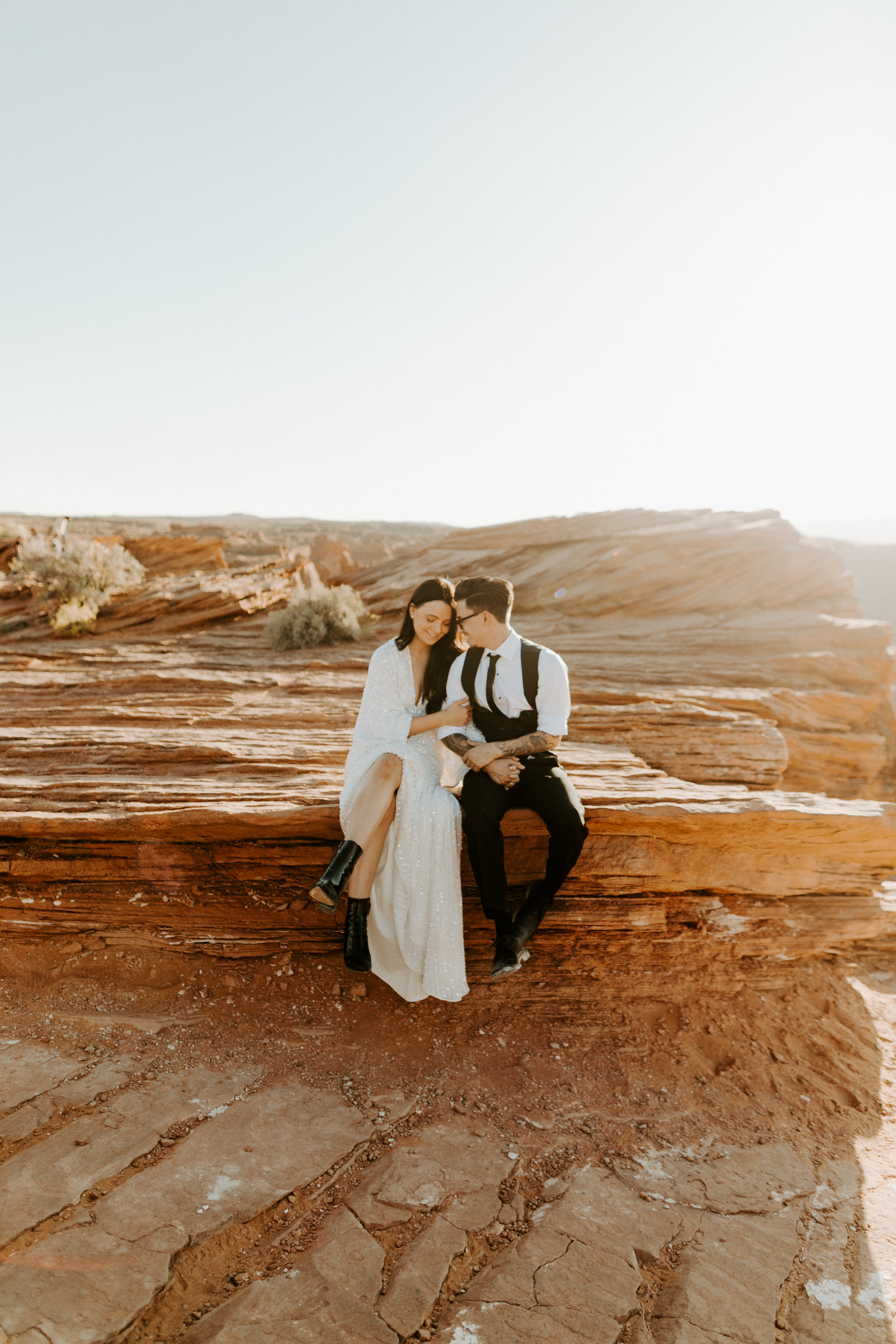  bride in an ivory long gown with bellowing sleeves and a boho design, groom in a black double-breasted vest and a white buttoned up shirt