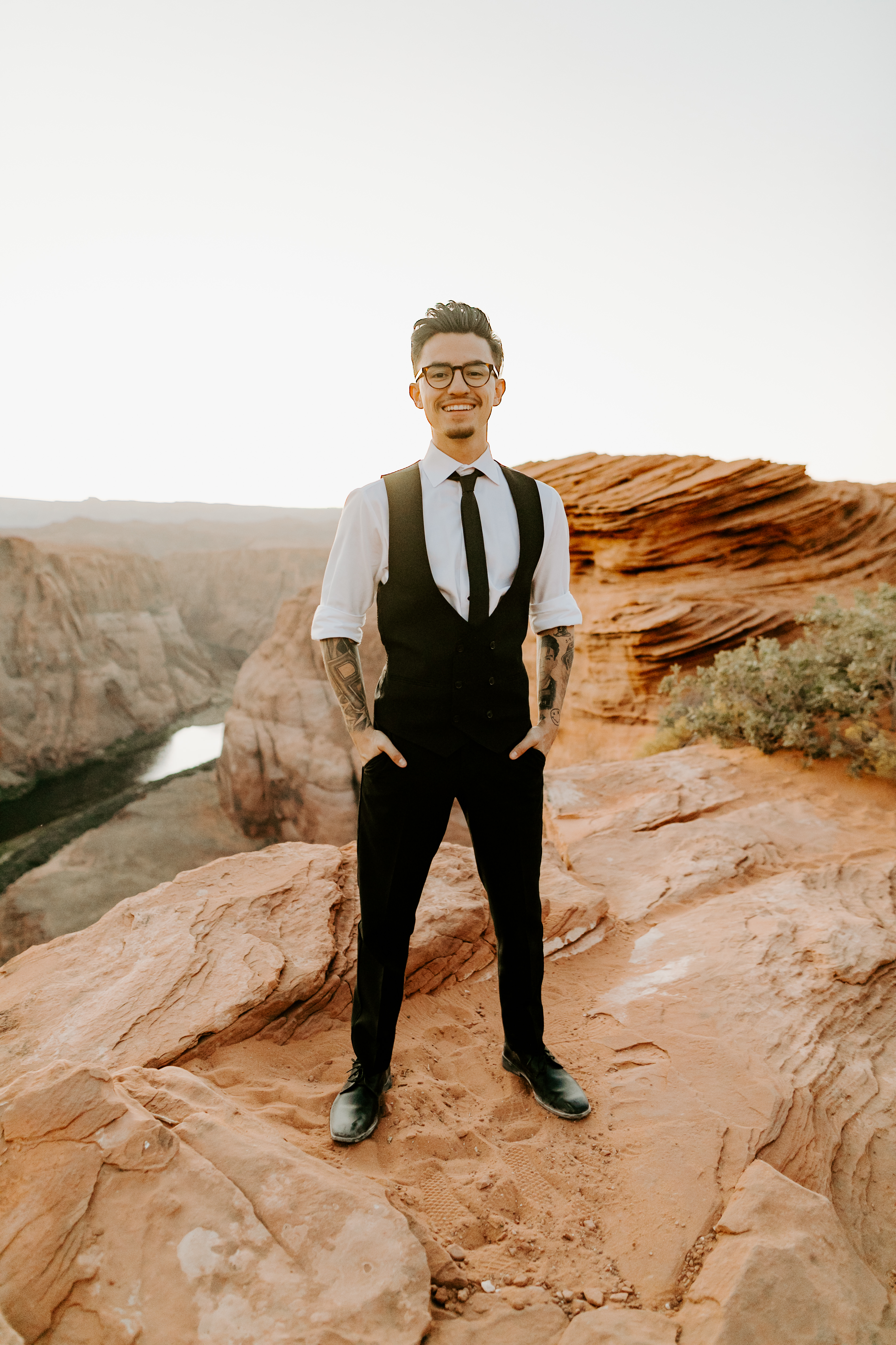  groom in a black double-breasted vest and a white buttoned up shirt on with his hands in his pockets