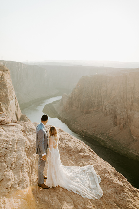  bride in an ivory lace gown with bellowing sleeves and a boho design, The groom is in a light blue suit with matching vest and no tie 