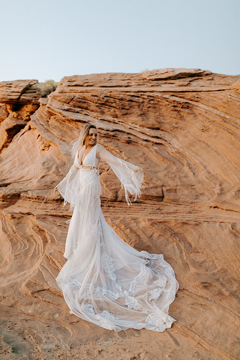  bride in an ivory lace gown with bellowing sleeves and a boho design standing